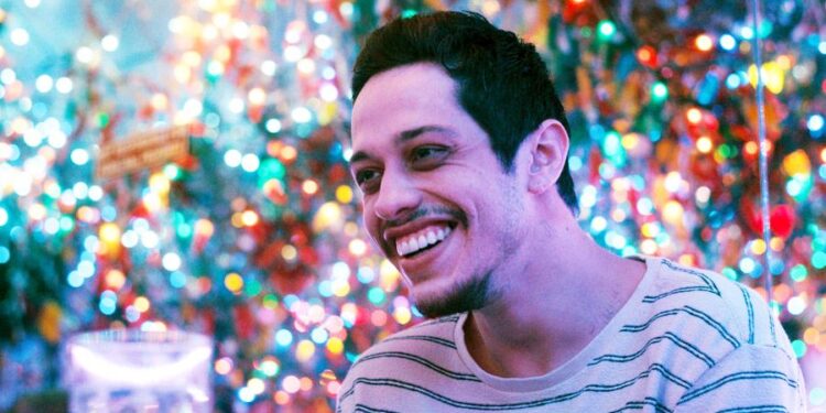 Pete Davidson as Gary, smiling in a brightly lit restaurant, in Meet Cute
