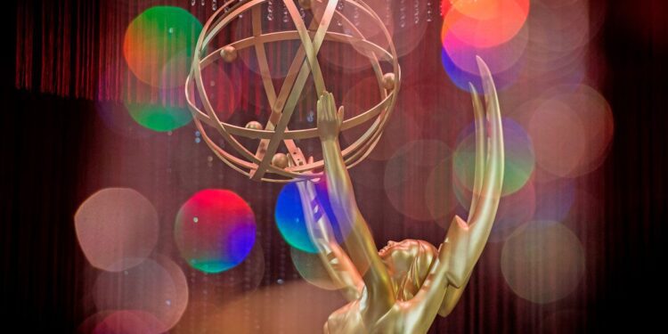 A gold Emmy statue in front of a colorful background