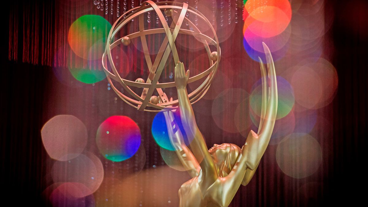 A gold Emmy statue in front of a colorful background