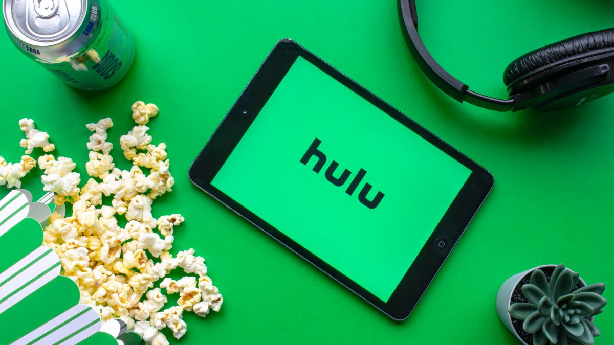 A tablet with the Hulu logo surrounded by popcorn, soda, headphones and a cactus