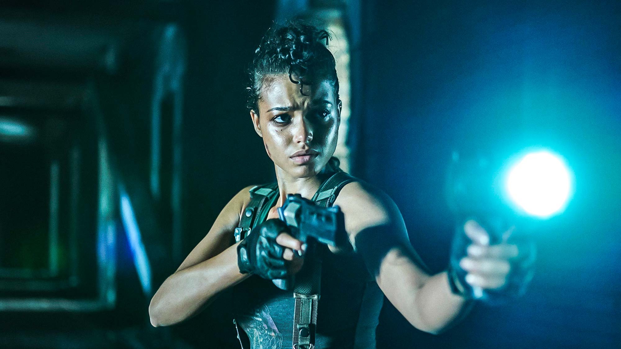 ELLA BALINSKA بدور JADE ، تحمل مسدسًا وبندقية مصباح يدوي في لعبة RESIDENT EVIL من Netflix