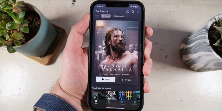 The new-look Netflix app shows a poster for Vikings: Valhalla on an iPhone