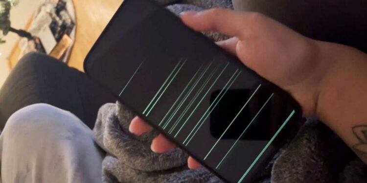 A photo of an iPhone 14 Pro Max showing green horizontal lines across the display